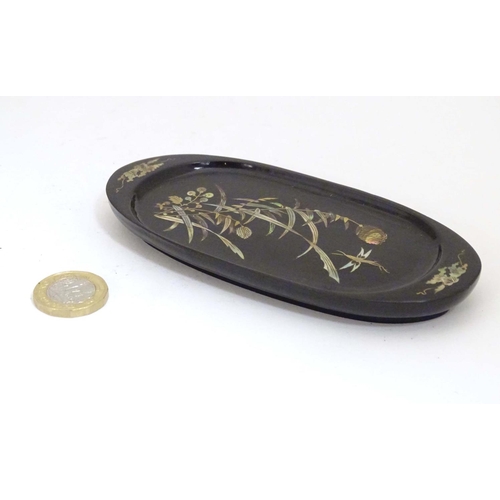 982 - An oval lacquered pin dish with inlaid abalone decoration depicting a stylised dragonfly with flower... 