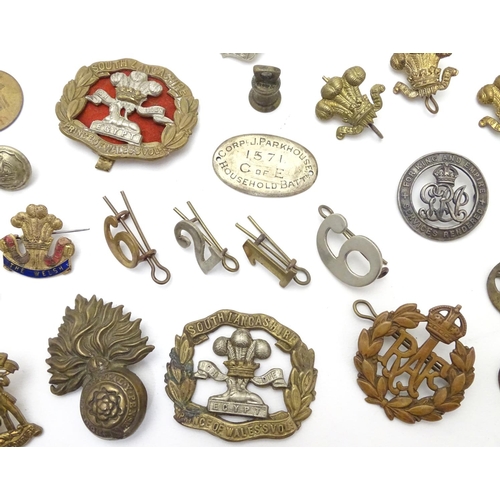 569 - Militaria: a collection of 20thC military badges, including an early 20thC white metal dog tag (insc... 