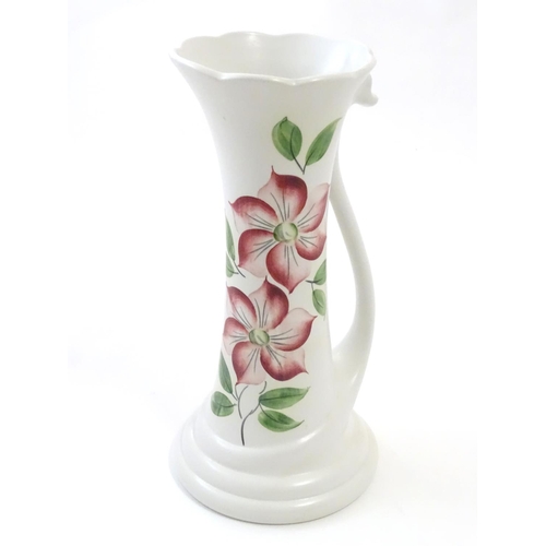 115 - An E Radford hand painted jug / vase with a tendril formed handle and hand painted clematis flower d... 