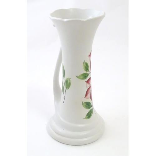 115 - An E Radford hand painted jug / vase with a tendril formed handle and hand painted clematis flower d... 