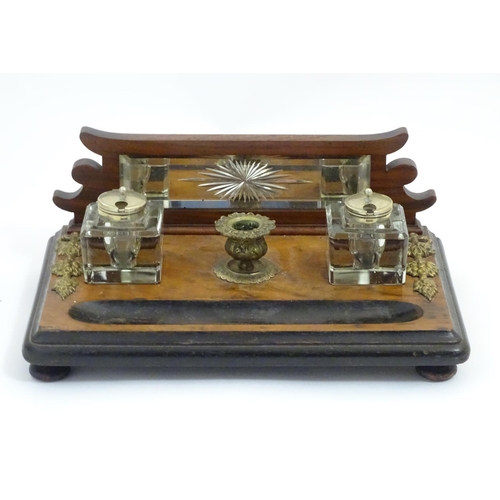 1004 - A Victorian desk standish with a central taper stick flanked by two glass inkwells, the base with ap... 