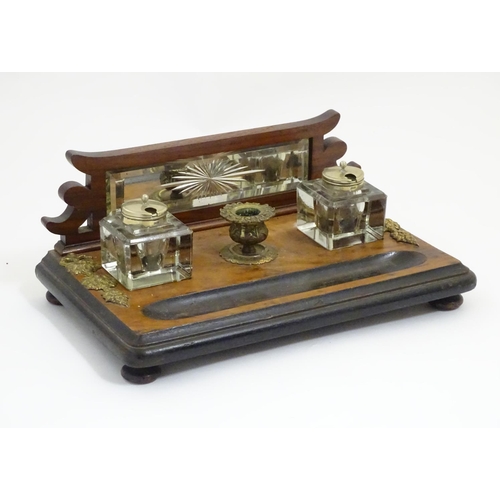 1004 - A Victorian desk standish with a central taper stick flanked by two glass inkwells, the base with ap... 