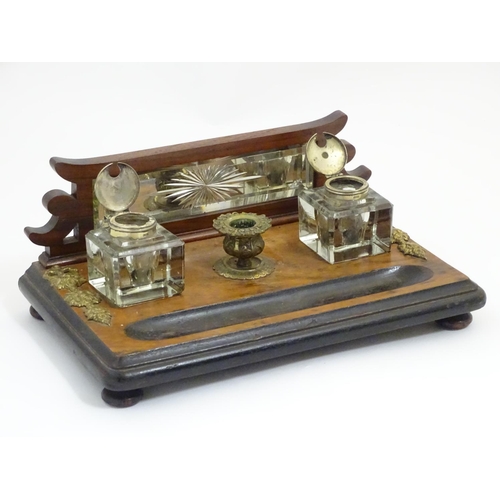 1004 - A Victorian desk standish with a central taper stick flanked by two glass inkwells, the base with ap... 