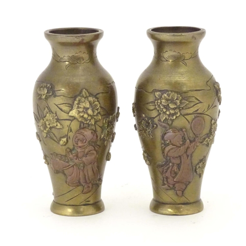 848 - A pair of late 19th / early 20thC miniature brass vases with engraved and relief decoration depictin... 