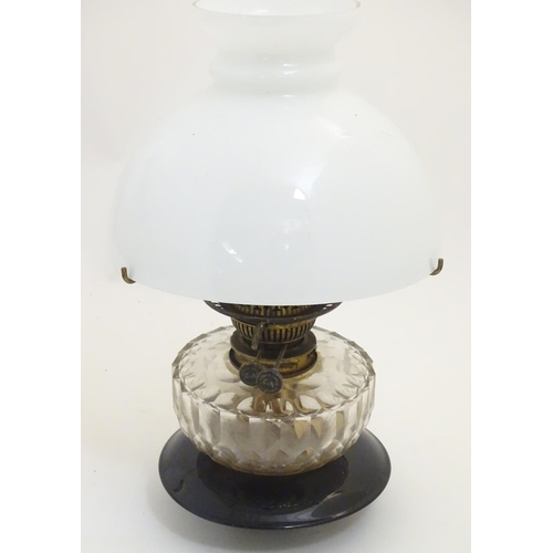 1524 - A 19thC oil lamp, the black glass base with facet cut glass reservoir and white milk glass shade. Th... 