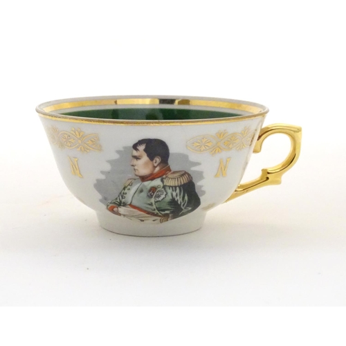 69 - A French tea cup and saucer depicting Emperor Napoleon with green and gilt highlights. Porcelaine de... 