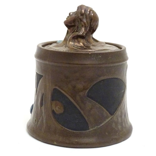 74 - A Bretby Art Nouveau tobacco pot with faux hammered copper effect and enamelled cabochon detail. The... 