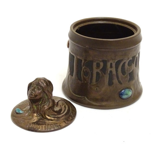 74 - A Bretby Art Nouveau tobacco pot with faux hammered copper effect and enamelled cabochon detail. The... 