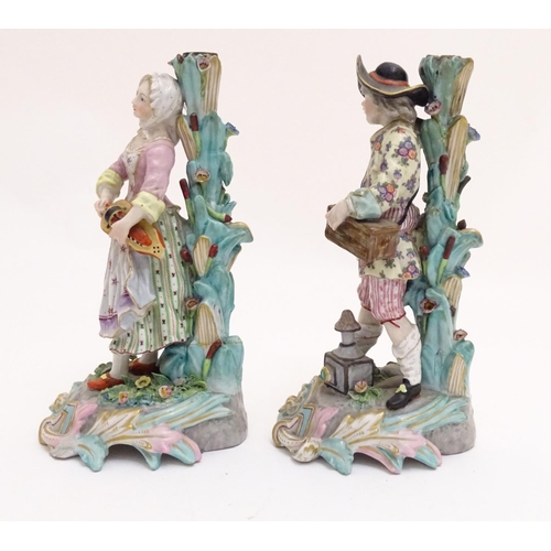 83 - A pair of 19thC Continental figural candlesticks, modelled as a man with a wooden box and lantern, a... 