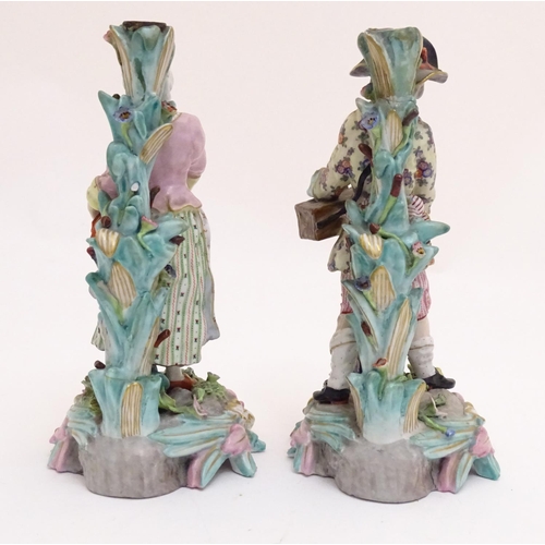 83 - A pair of 19thC Continental figural candlesticks, modelled as a man with a wooden box and lantern, a... 