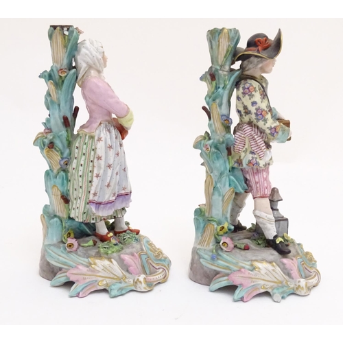 83 - A pair of 19thC Continental figural candlesticks, modelled as a man with a wooden box and lantern, a... 