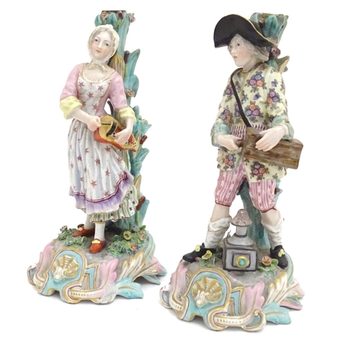 83 - A pair of 19thC Continental figural candlesticks, modelled as a man with a wooden box and lantern, a... 