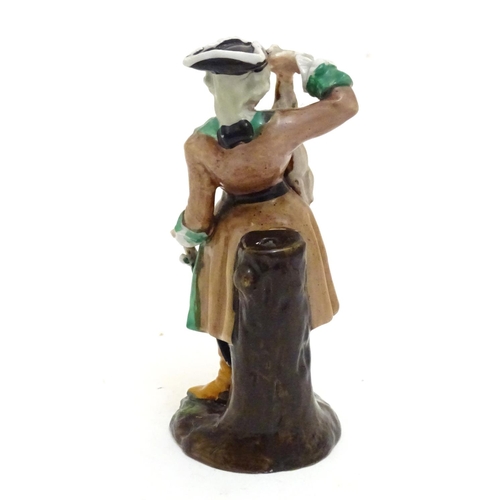 85 - A Continental porcelain figure modelled as a man in a tricorn hat holding dead game / rabbit, on a n... 