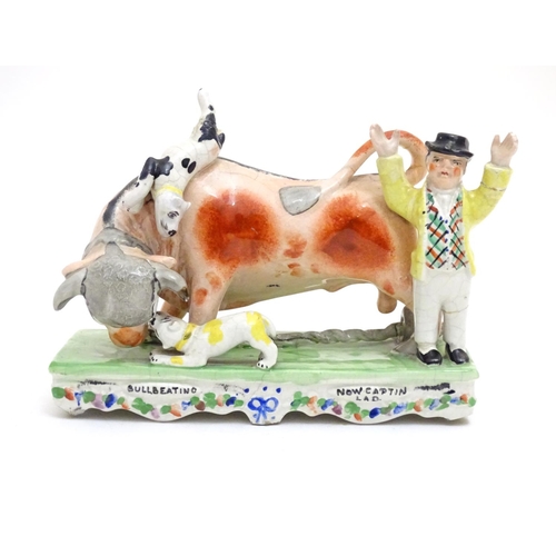 89 - A Victorian Staffordshire bull baiting figural group, depicting a bull fight with two dogs and a cap... 