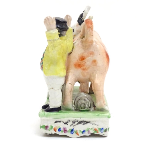 89 - A Victorian Staffordshire bull baiting figural group, depicting a bull fight with two dogs and a cap... 