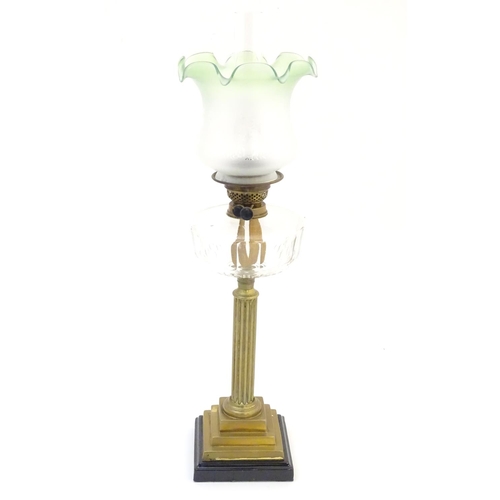 1519 - A late 19thC / early 20thC oil lamp, the brass column on stepped base supporting a clear cut glass r... 