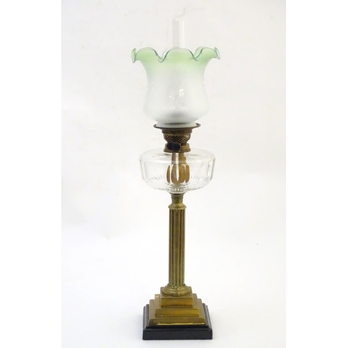 1519 - A late 19thC / early 20thC oil lamp, the brass column on stepped base supporting a clear cut glass r... 