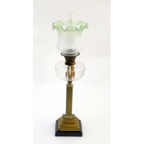 1519 - A late 19thC / early 20thC oil lamp, the brass column on stepped base supporting a clear cut glass r... 