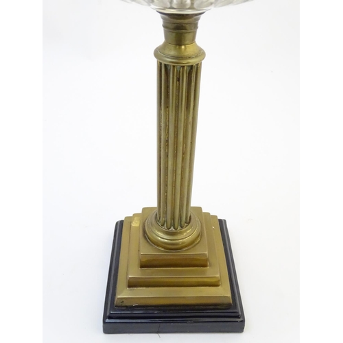 1519 - A late 19thC / early 20thC oil lamp, the brass column on stepped base supporting a clear cut glass r... 