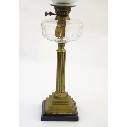 1519 - A late 19thC / early 20thC oil lamp, the brass column on stepped base supporting a clear cut glass r... 