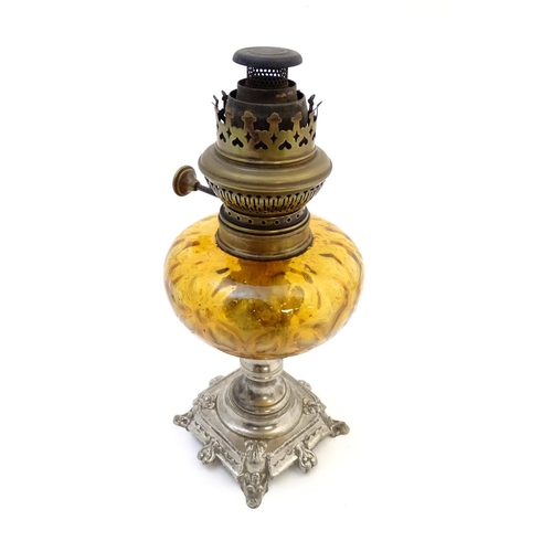 1523 - A late 19thC / early 20thC Continental oil lamp wit amber glass reservoir and clear glass chimney. T... 