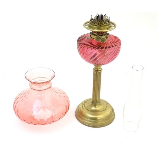 1526 - A Victorian oil lamp, the brass column with cranberry glass reservoir and shade. The twin burners ma... 