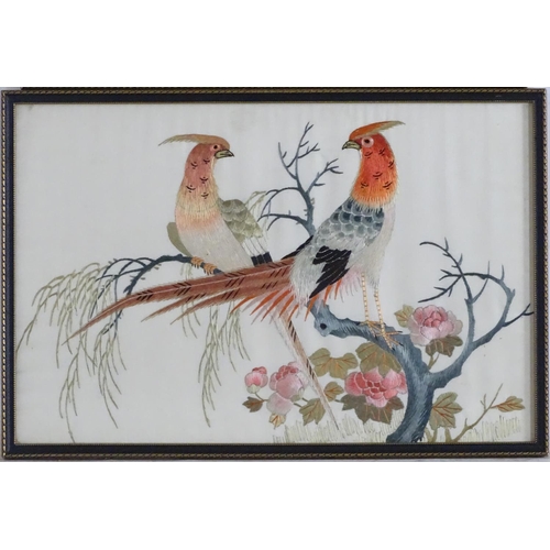 1761 - Two oriental silk embroideries depicting stylised golden pheasant birds perched on branches, with fl... 