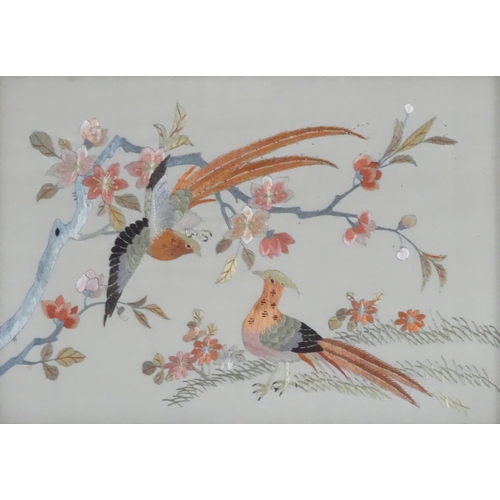 1761 - Two oriental silk embroideries depicting stylised golden pheasant birds perched on branches, with fl... 