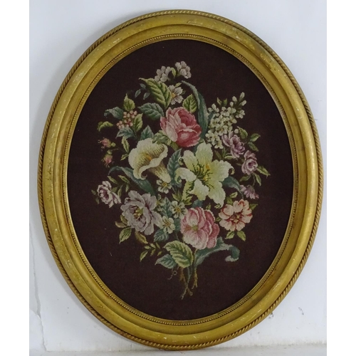 1765 - A Victorian oval woolwork embroidery / needlework depicting a floral display with lilies, roses toge... 