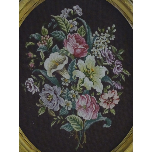 1765 - A Victorian oval woolwork embroidery / needlework depicting a floral display with lilies, roses toge... 