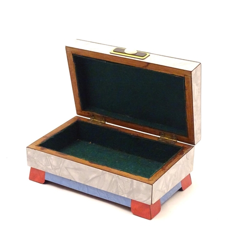 844 - An Art Deco box with a hinged lid with formica veneers and celluloid roundels etc. Approx. 4 1/4