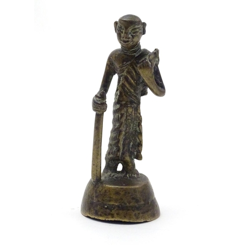 847 - An Oriental brass figure modelled as a man with a staff. Approx. 4 1/2