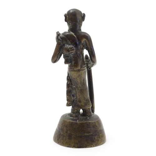 847 - An Oriental brass figure modelled as a man with a staff. Approx. 4 1/2