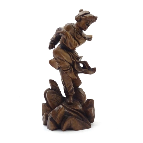 849 - An Oriental carved wooden figure modelled as man on a rocky outcrop with foliate detail. Approx. 12 ... 