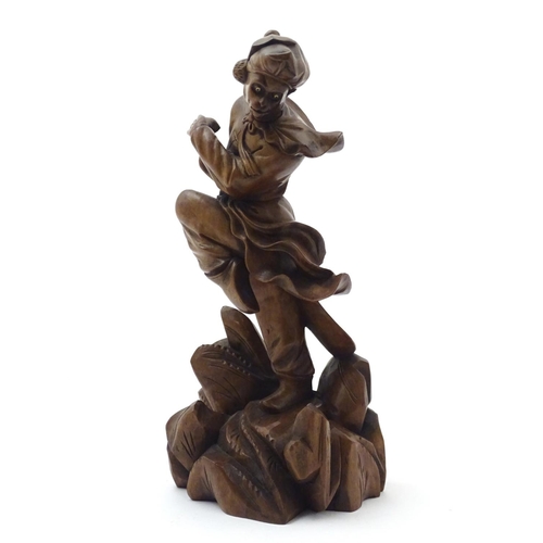 849 - An Oriental carved wooden figure modelled as man on a rocky outcrop with foliate detail. Approx. 12 ... 