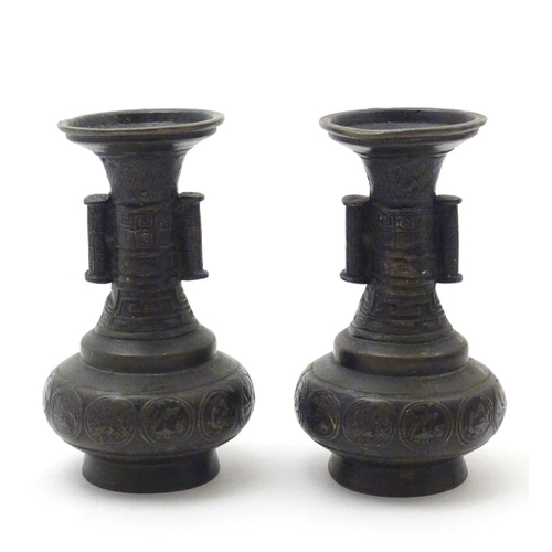 850 - A pair of cast Oriental vases with flared rims, twin handles and relief decoration. Approx. 4 3/4