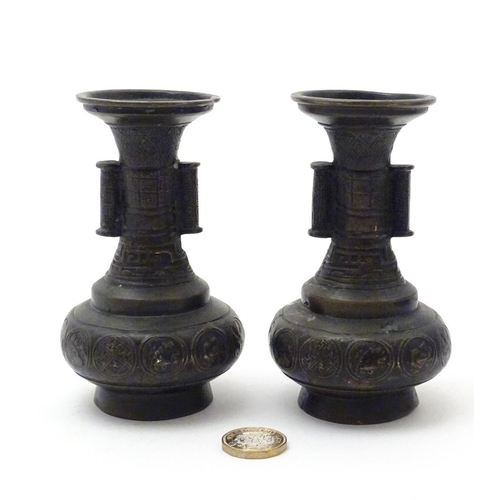 850 - A pair of cast Oriental vases with flared rims, twin handles and relief decoration. Approx. 4 3/4