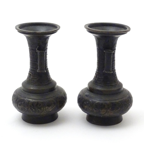 850 - A pair of cast Oriental vases with flared rims, twin handles and relief decoration. Approx. 4 3/4