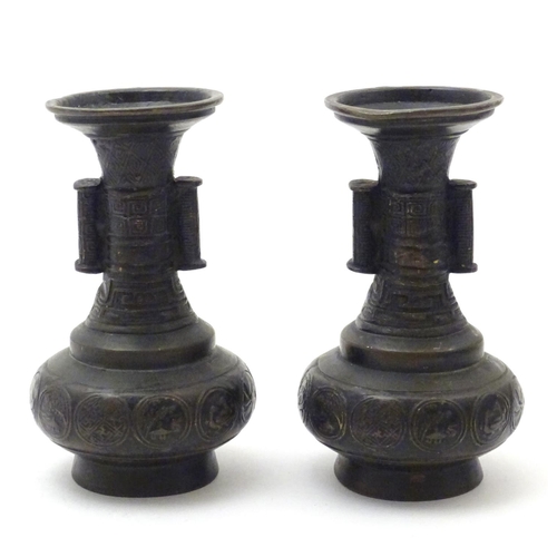 850 - A pair of cast Oriental vases with flared rims, twin handles and relief decoration. Approx. 4 3/4