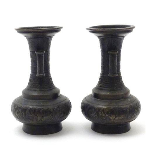 850 - A pair of cast Oriental vases with flared rims, twin handles and relief decoration. Approx. 4 3/4