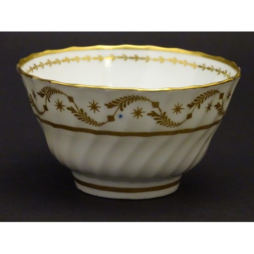 109 - A 19thC white porcelain tea bowl with ribbed sides and gilt decoration of stylised foliage and stars... 