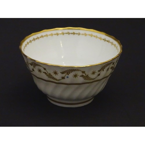 109 - A 19thC white porcelain tea bowl with ribbed sides and gilt decoration of stylised foliage and stars... 