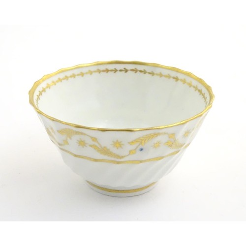 109 - A 19thC white porcelain tea bowl with ribbed sides and gilt decoration of stylised foliage and stars... 