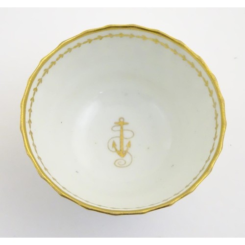 109 - A 19thC white porcelain tea bowl with ribbed sides and gilt decoration of stylised foliage and stars... 