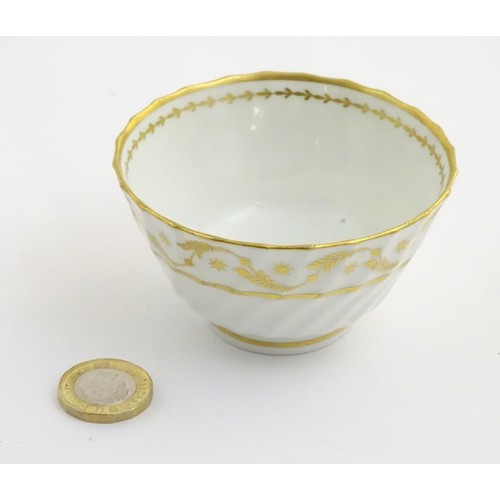 109 - A 19thC white porcelain tea bowl with ribbed sides and gilt decoration of stylised foliage and stars... 