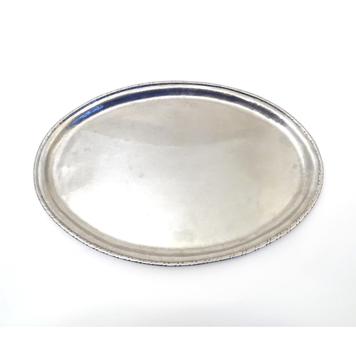 813 - An early 20thC Hugh Wallis oval hammered tray. Stamped with HW monogram. Approx. 13 1/4