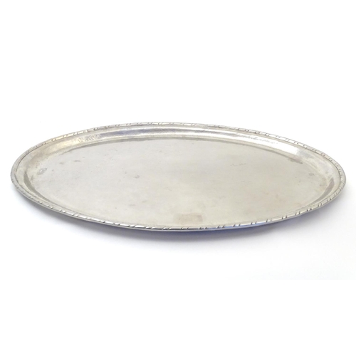 813 - An early 20thC Hugh Wallis oval hammered tray. Stamped with HW monogram. Approx. 13 1/4