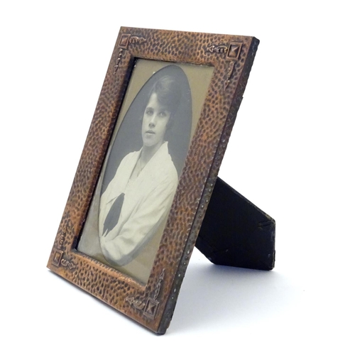 814 - An Arts & Crafts copper photograph frame with hammered decoration and embossed corner detail. Approx... 