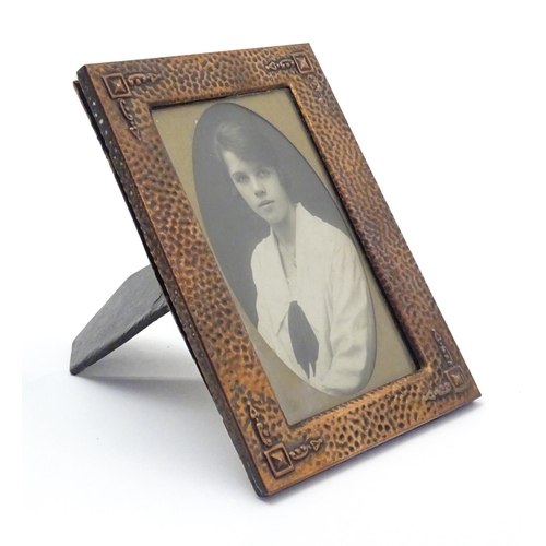 814 - An Arts & Crafts copper photograph frame with hammered decoration and embossed corner detail. Approx... 