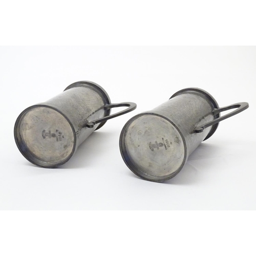 817 - A pair of Arts & Crafts pewter vases of cylindrical form with twin handles and hammered decoration b... 